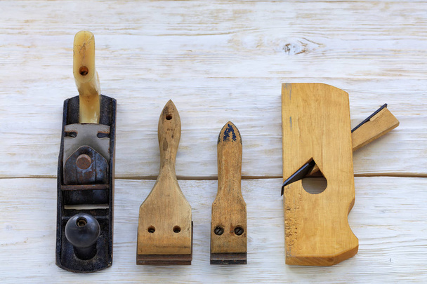 Старі столярні інструменти лежать на білому дерев'яному столі
. - Фото, зображення
