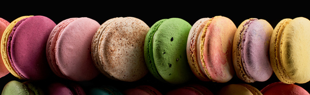 row of colorful French macaroons of different flavors isolated on black, panoramic shot - Φωτογραφία, εικόνα