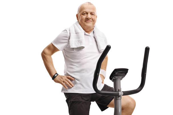Elderly man sitting on an exercise bike and looking at the camer - Foto, immagini