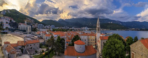 El casco antiguo de Budva al atardecer desde la ciudadela con la iglesia de la Santísima Trinidad, el mar Adriático y la playa de Richard 's Head en Montenegro
 - Foto, Imagen