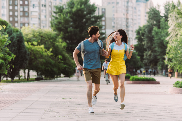 knappe man en Aziatische vrouw rennen en kijken naar elkaar  - Foto, afbeelding
