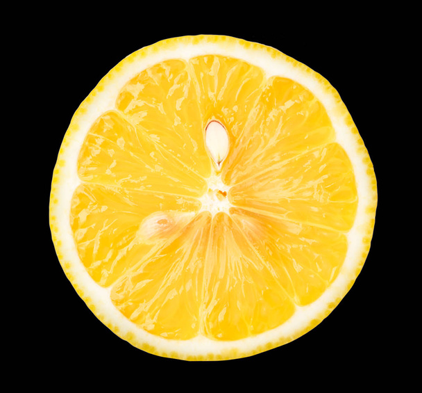 Half a fresh lemon with a bone, isolated on a black background. - Photo, Image