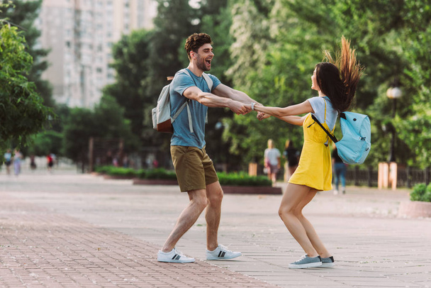 handsome man and woman smiling, jumping and holding hands  - Photo, Image
