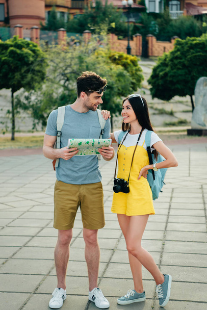 handsome man holding map and looking at asian woman  - Φωτογραφία, εικόνα