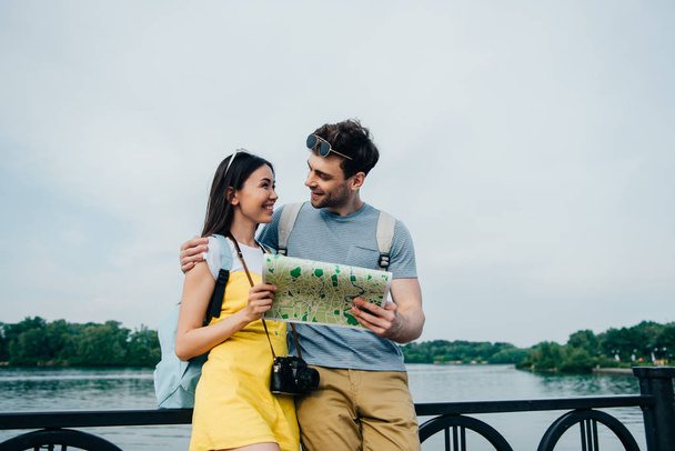 handsome man holding map and looking at asian woman  - Photo, Image