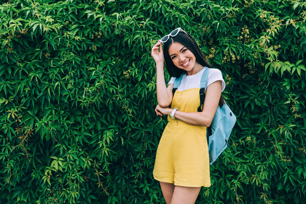 asiático y atractivo mujer en amarillo overoles sonriendo y mirando a cámara
  - Foto, imagen