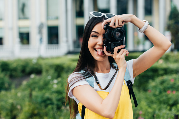 attractive and asian woman with glasses sticking out tongue and taking photo   - Fotoğraf, Görsel