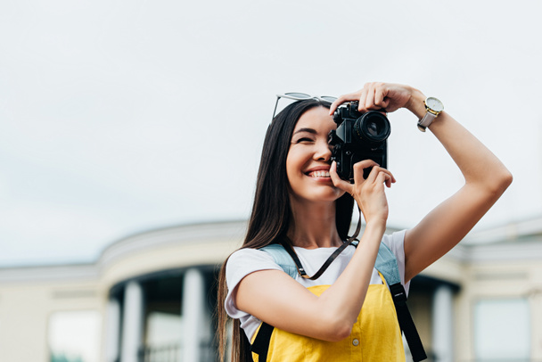 attractive and asian woman with glasses smiling and taking photo  - Fotografie, Obrázek
