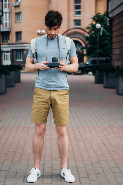jóvágású ember-ban t-ing és rövidnadrág látszó-on digitális fényképezőgép - Fotó, kép