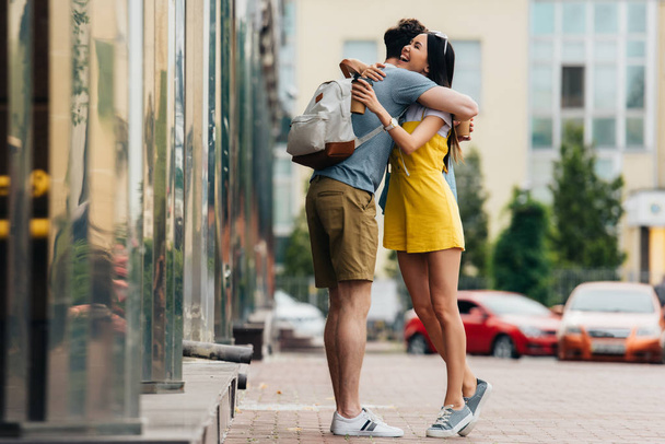 man with backpack and asian woman hugging and holding paper cups  - Photo, image