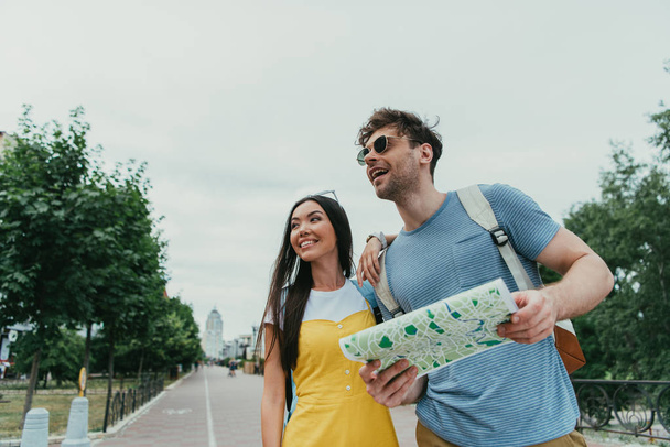 handsome man holding map and asian woman looking away - Photo, Image