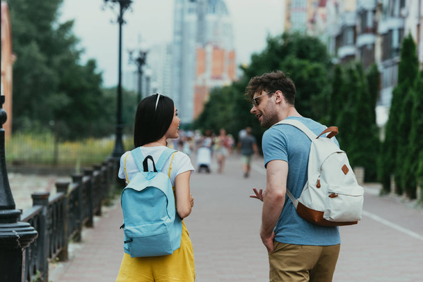 back view of man and woman with backpacks talking outside  - Foto, Imagen