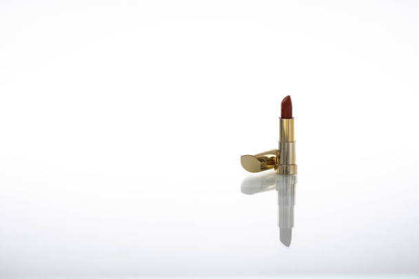 Ciemnoczerwona szminka ze złotą obudową z refleksją na temat szkła na białym tle - Zdjęcie, obraz