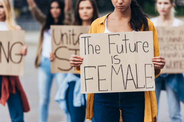 περικομμένη θέα του κοριτσιού κρατώντας πλακάτ με επιγραφή το μέλλον είναι γυναίκες κοντά φεμινίστριες στο δρόμο - Φωτογραφία, εικόνα