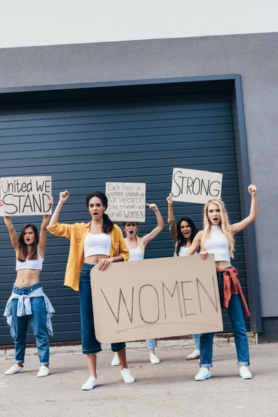 full length view of screaming multiethnic feminists holding placards with slogans on street - Photo, Image