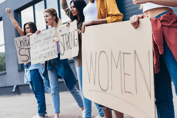 cropped view of feminists holding placard with word women on street - Fotoğraf, Görsel