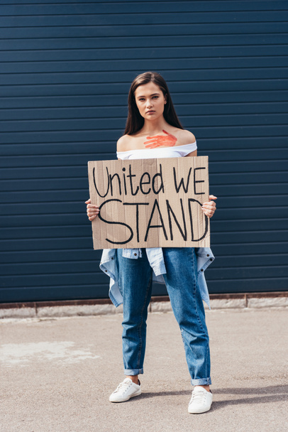 full length view of feminist holding placard with inscription united we stand on street - Foto, imagen