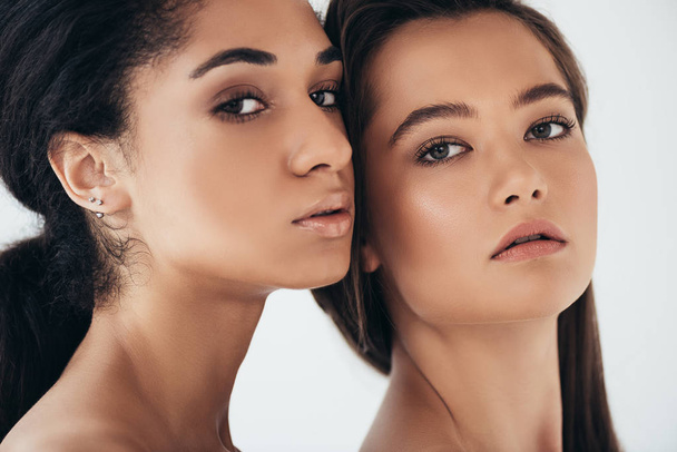 two attractive multiethnic young women looking at camera isolated on grey - Foto, Imagem
