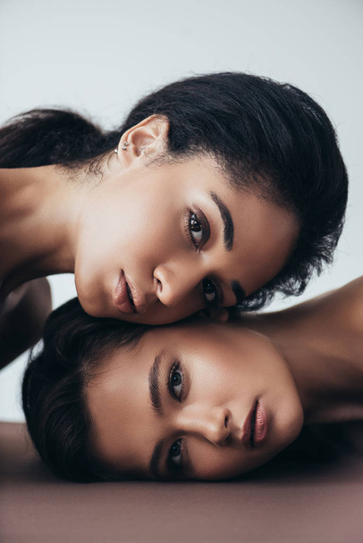 two attractive sensual multiethnic young women looking at camera isolated on grey - Fotó, kép