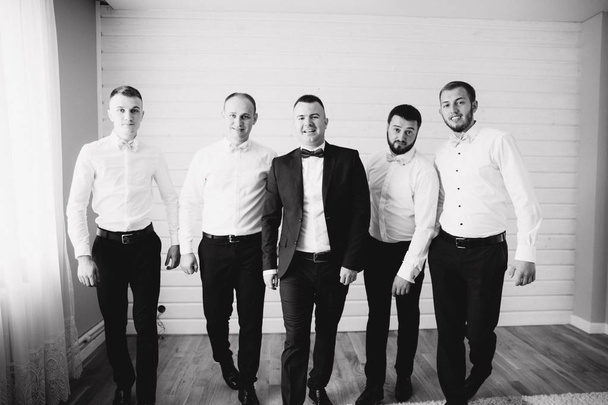 Handsome groom with his groomsman at home. Five man. Groom dressed in suit, gromsmen in white shirt. Funny guys on the wedding - Photo, Image