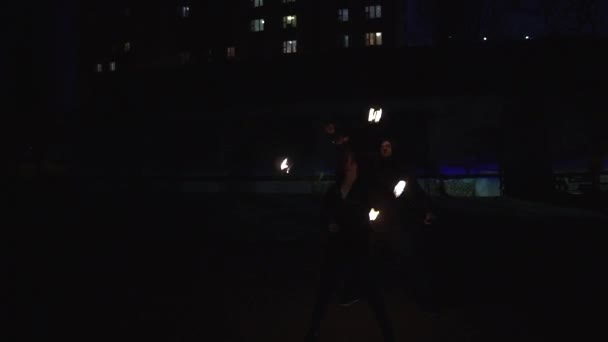 Два жонглера крутят огненные шары впечатляюще глубоко ночью на улице.
 - Кадры, видео