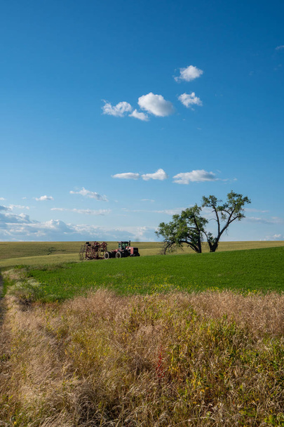 Hylätty traktori ja viljelylaitteet avoimella pellolla lähellä
  - Valokuva, kuva