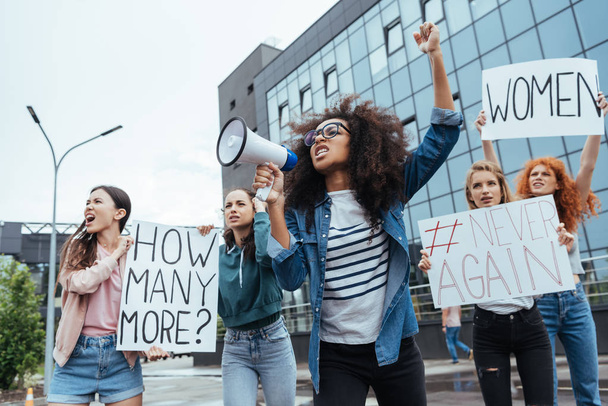 enfoque selectivo de chica afroamericana gesto mientras sostiene el megáfono cerca de las niñas en la reunión
  - Foto, Imagen