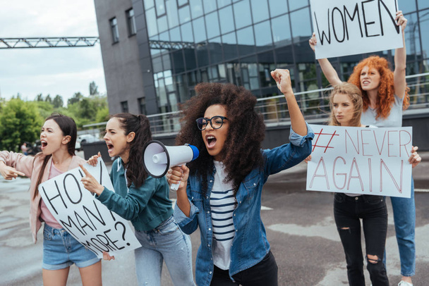 enfoque selectivo de chica afroamericana gesto mientras sostiene el megáfono y grita cerca de las niñas en la reunión
  - Foto, imagen