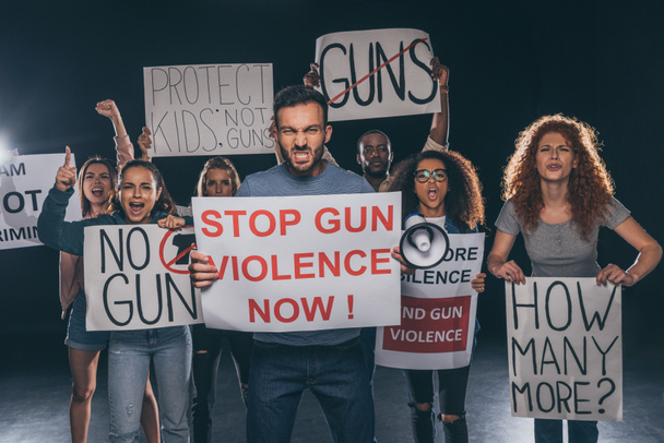hombre enojado sosteniendo pancarta con stop gun violencia ahora letras cerca de personas multiculturales en negro
  - Foto, Imagen