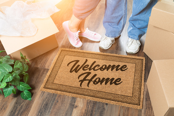 Man and Woman Unpacking Near Welcome Home Welcome Mat, Moving Boxes and Plant - Photo, image