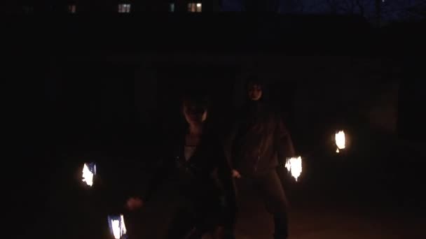 Smiling girl and young man stand behind each other and rotate fireballs at night in slo-mo - Footage, Video