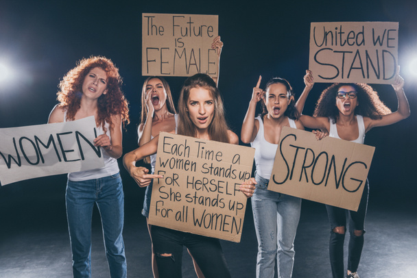 ελκυστικές πολυπολιτισμικές γυναίκες φωνάζοντας και κρατώντας πλακάτ σε μαύρο   - Φωτογραφία, εικόνα