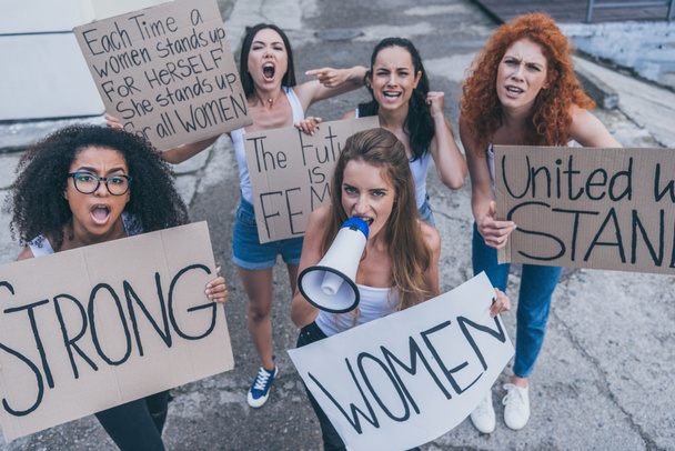 beautiful multicultural girls holding placards and screaming outside  - Photo, Image