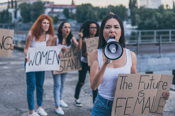 selective focus of emotional girl holding placard with the future is female letters and screaming in megaphone outside  - Foto, imagen