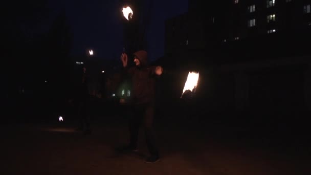 Mujer y hombre muestran a la gente en trajes negros girando bolas de fuego en la noche en slo-mo
 - Imágenes, Vídeo