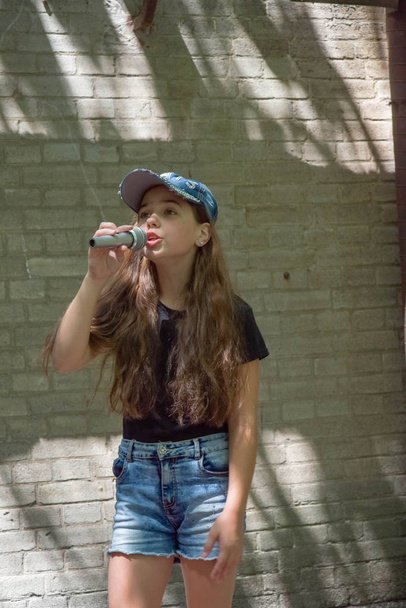 Menina bonita com microfone no fundo da parede de tijolo
 - Foto, Imagem
