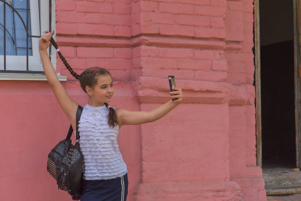 close up πορτρέτο του μικρό όμορφο κομψό παιδί κορίτσι κοντά στο κόκκινο τοίχο ως φόντο - Φωτογραφία, εικόνα
