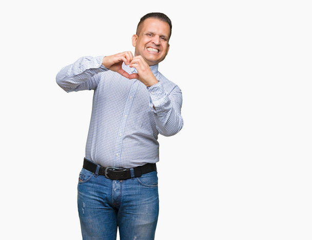 Арабський бізнесмен середнього віку над ізольованим тлом посміхається в любові, демонструючи символ серця і форму руками. Романтична концепція
. - Фото, зображення