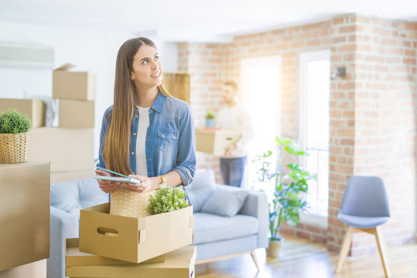 Young couple moving to a new home, beautiful woman smiling moving cardboard box - Foto, Bild
