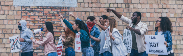 plano panorámico de personas multiculturales caminando cerca de la pared de ladrillo durante la protesta
  - Foto, Imagen