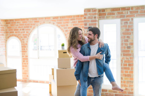 Young couple moving to a new house, boyfriend giving a piggy back - Foto, Bild