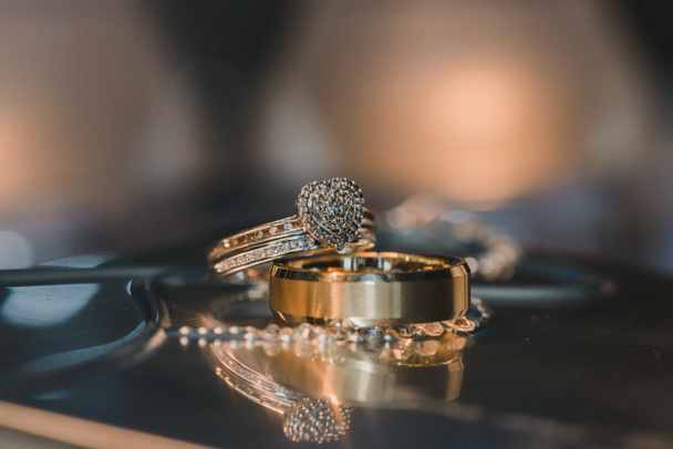 Gold heart wedding rings with diamonds on reflective table - Photo, Image