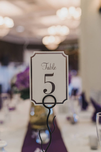 Wedding Receptie tafel nummer vijf plaats kaart op paarse tafel instelling - Foto, afbeelding