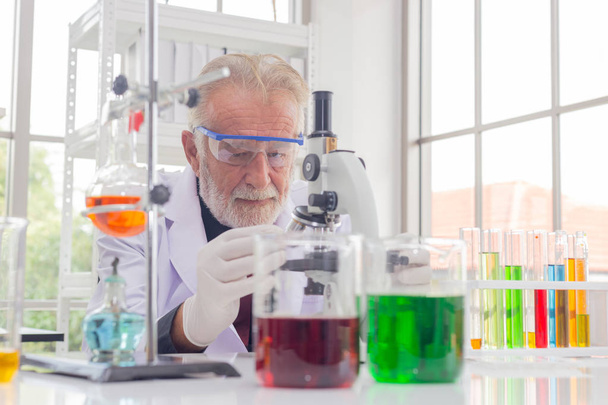 Senior Scientist hält Reagenzglas mit Reagenz im Labor. - Foto, Bild