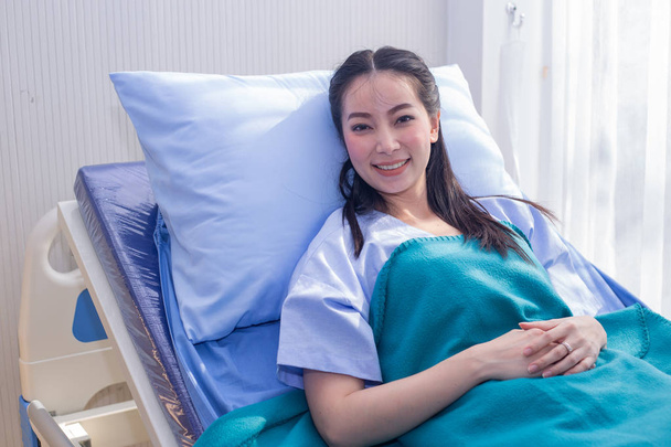 Asian kobieta pacjenta, który ma lepsze objawy na łóżku szpitalnym. - Zdjęcie, obraz