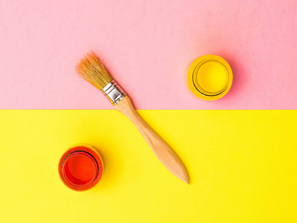 Brushes and jars with bright paint on a background of two colors of paper. Creative kit. - Photo, Image