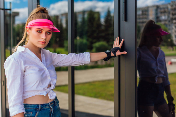 Portrait d'une fille émotionnelle dans une visière à casquette rose et gants de protection pour rollers et skateboard
. - Photo, image