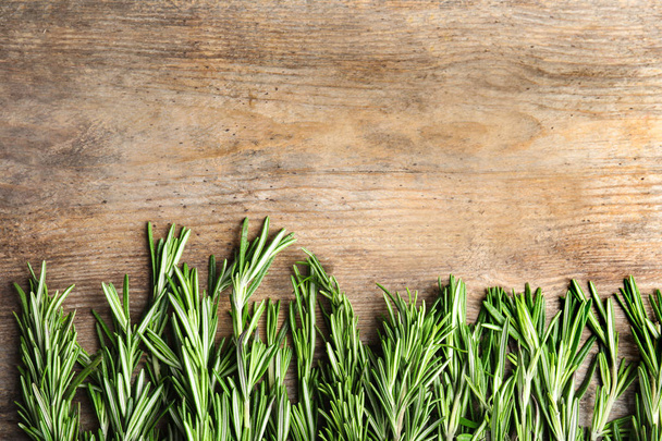 Branches of fresh rosemary on wooden table, top view with space for text - Fotografie, Obrázek