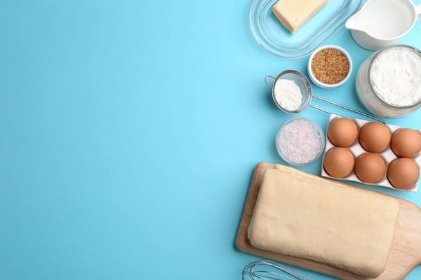 Puff pastry dough and ingredients on light blue background, flat lay. Space for text - 写真・画像