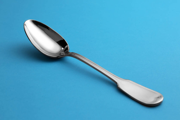 Clean empty tea spoon on blue background - Zdjęcie, obraz